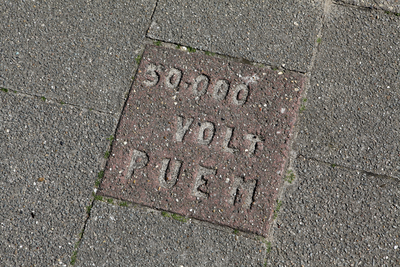 913967 Afbeelding van de stoeptegel met tekst '50.000 Volt PUEM' in de Cornelis Mertenssstraat te Utrecht.